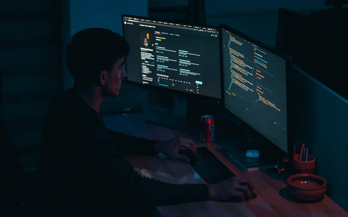 An engineer working late across two monitors of code