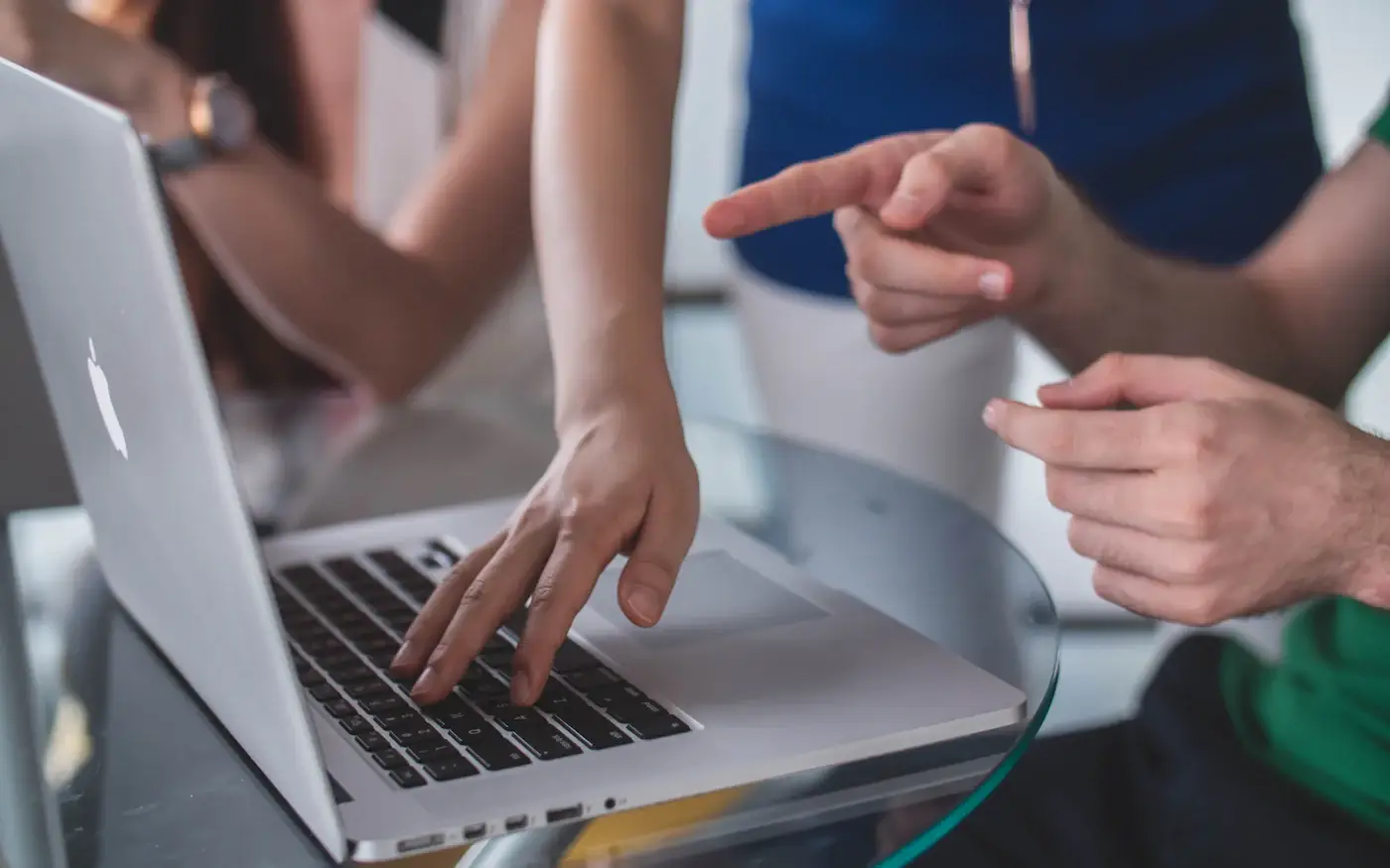 A senior engineer pointing at a junior colleague's laptop screen