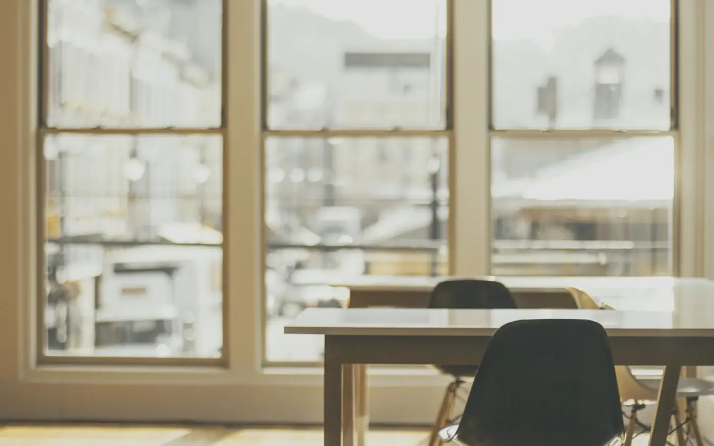 An empty desk and chair by a bright office window