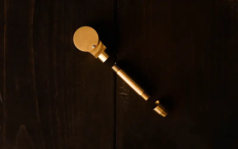 A single brass key on a dark wooden surface